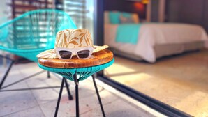 Una habitación con una cama, una silla y una mesa con un sombrero y gafas de sol.