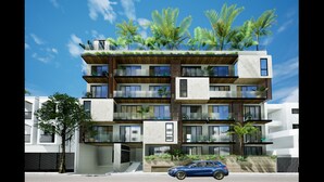 Un moderno edificio residencial de varios pisos, con balcones, ventanas amplias y áreas verdes.