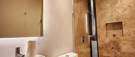 A modern bathroom with a large mirror, a sink, a toilet, and a shower.