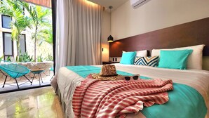 Habitación de hotel con una cama, vista a palmeras y un balcón con sillas.