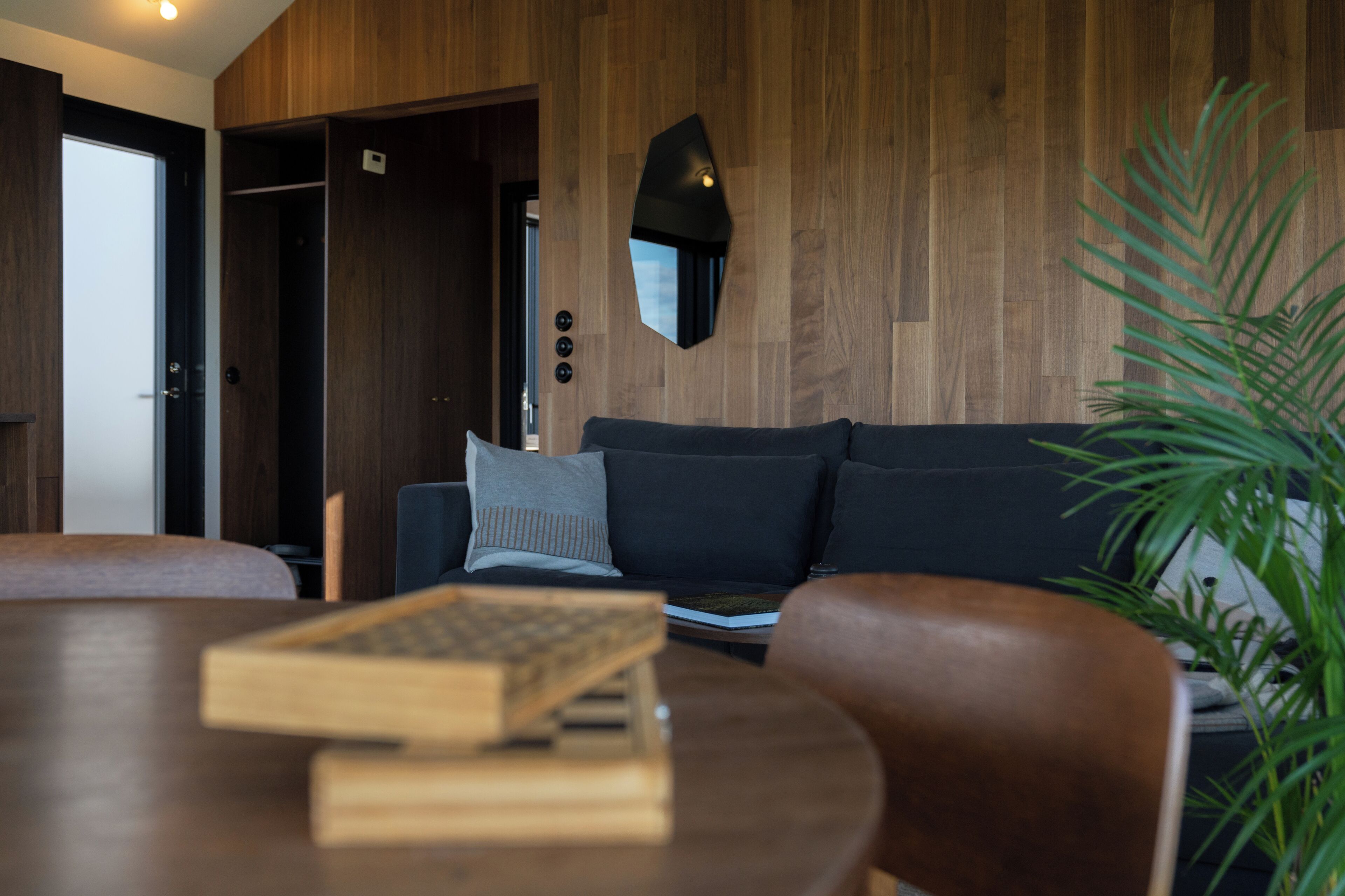 En moderne stue med en mørk sofa, et træsofa bord og en potteplante.
