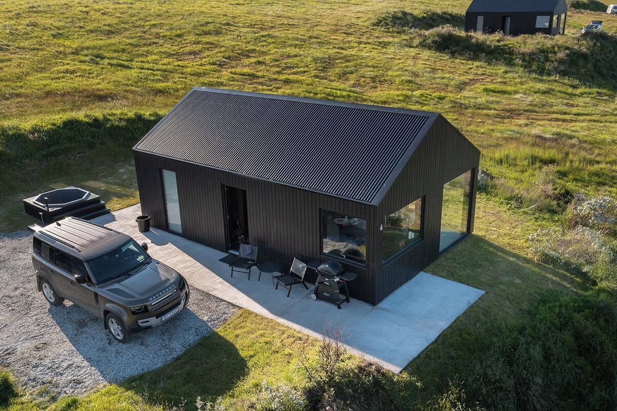 A modern house with a sloped roof, a patio with outdoor seating, and a gravel driveway.