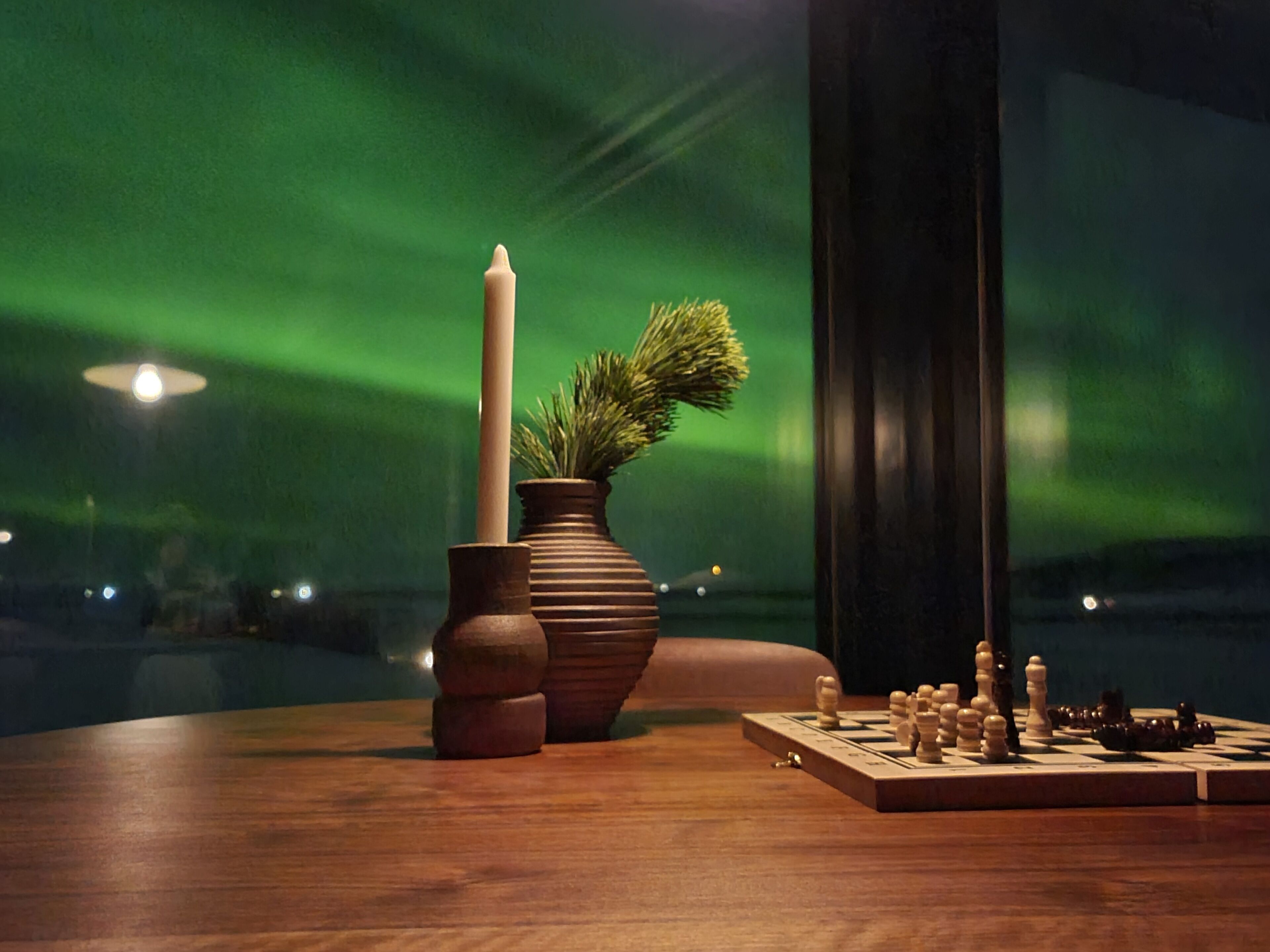Una mesa de madera con un tablero de ajedrez y dos jarrones, uno con una planta.