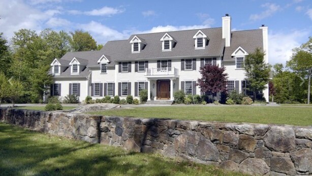 A large, two-story house with a stone wall in front, multiple windows, and a well-maintained lawn. - Over Sized Colonial on Private Road.  (Pound Ridge)