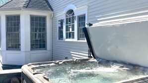 A hot tub in front of a house with a covered patio and a windowed room. - Over Sized Colonial on Private Road.  (Pound Ridge)