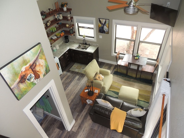 Amplia sala de estar con sofá, una mesa de comedor y zona de cocina con estanterías de madera.