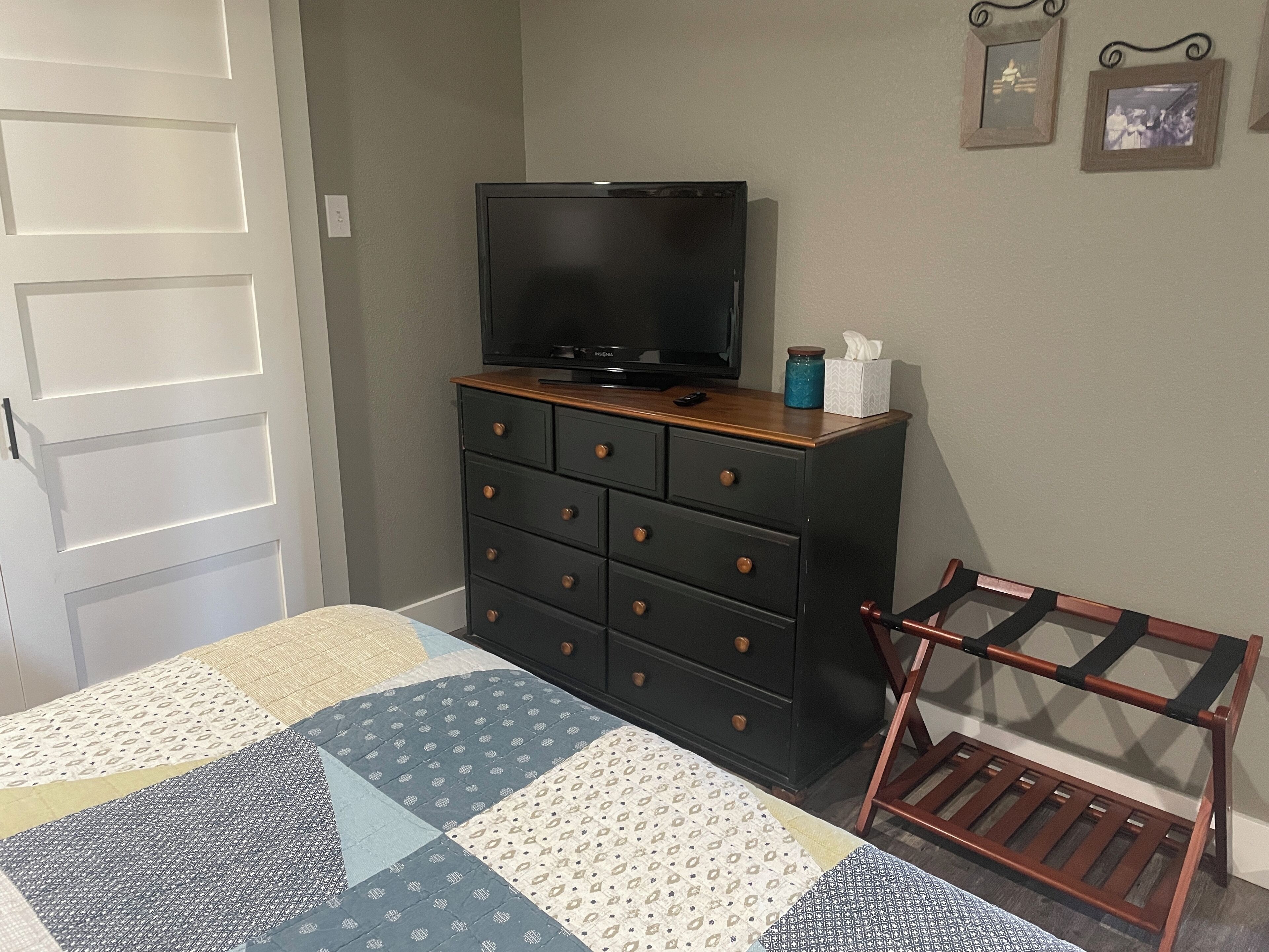 Un dormitorio con una cama, un aparador con televisor y una silla.