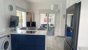 A modern kitchen with a built-in washing machine, a flat-screen TV, and a large refrigerator. - Villa 400 Meters Walk To The Beach, Sleep 6, 3 Bedrooms, 5 beds (sotira)