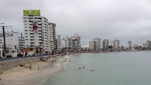 Una spiaggia con una fila di edifici a più piani, alcuni con insegne visibili.