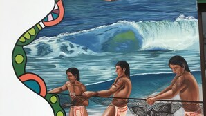 Un murale raffigura una nave a vela su una spiaggia con onde che si infrangono.