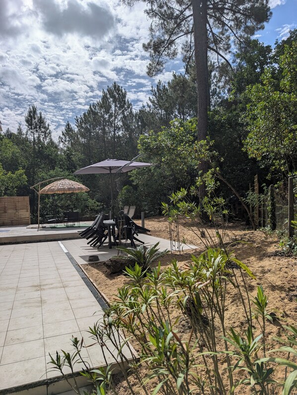 An outdoor patio area with a table and chairs, surrounded by trees and plants.