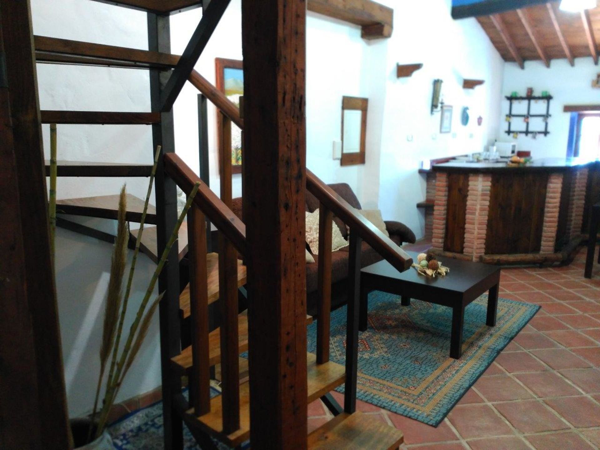 Una escala de fusta amb una catifes i una taula en un interior rústic.