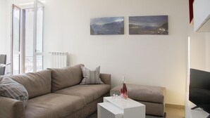 Una sala moderna con un sofá color beige, una mesa de centro blanca y dos cuadros con paisajes en la pared.