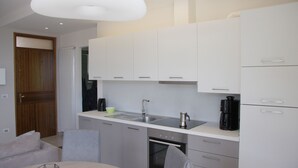 Una cocina moderna con armarios blancos, electrodomésticos de acero inoxidable y una zona de comedor con una mesa redonda y sillas.