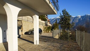 A stone-paved driveway leading to a building with a balcony overlooking a mountainous landscape.