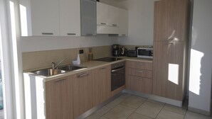 A modern kitchen with white and wood cabinets, stainless steel appliances, and a tiled floor.