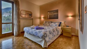 Un dormitorio con una cama grande, una mesita de noche, una ventana con cortinas, un cartel en la pared y un cuadro.