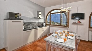 A modern kitchen with a dining area, a microwave, a sink, and a television. - Armonia by Theater Home, with two parking spaces and beautiful lake view (Tignale)