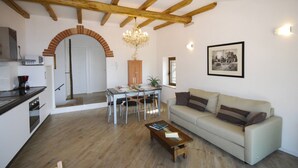 A living room with a sofa, a coffee table, and a dining area with chairs and a table. - Gina by Theater Home, in the historic centre with beautiful lake view (Tignale)