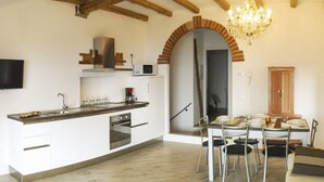 A modern kitchen with a built-in oven, a microwave, and a coffee maker. There is a dining area with a table and chairs. - Gina by Theater Home, in the historic centre with beautiful lake view (Tignale)