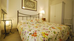 A bedroom with a bed, a bedside table with a lamp, a wardrobe, and a framed picture on the wall. - Menèk by Theater Home, in the historic centre (Tignale)