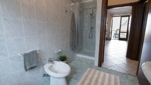 A bathroom with a shower, bidet, and a small plant. - Michela 2 by Theater Home, with lake view (Tignale)