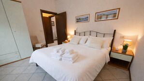 A neatly made bed with towels, a bedside table with a lamp, and a door leading to another room. - Michela 2 by Theater Home, with lake view (Tignale)