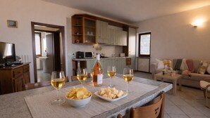 Un coin repas avec une table dressée pour quatre personnes, une bouteille de vin et deux bols de chips.