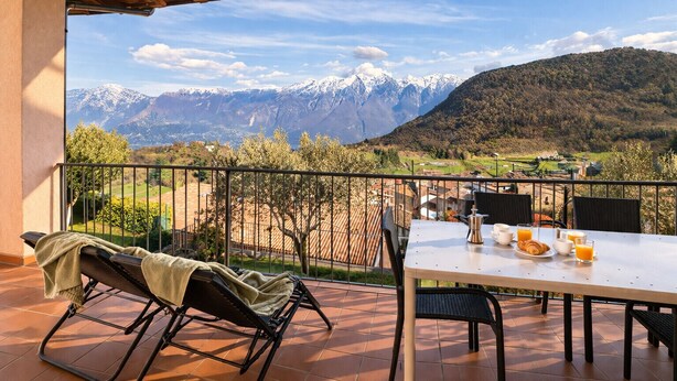 Une terrasse avec une table dressée pour le petit-déjeuner, une chaise et une vue sur des montagnes enneigées.