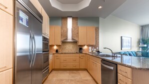 Una cocina moderna con electrodomésticos de acero inoxidable, armarios de madera y salpicadero de azulejos.