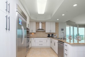 A modern kitchen with stainless steel appliances, white cabinetry, and a large island with a sink. - CRC1215 4BR/3.5BA Orange Beach condo w/ beach view (Orange Beach)