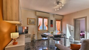 Ein modernes Wohnzimmer mit Fernseher, Esstisch und einer Couch.
