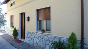 Ein Gebäude mit Steinstufen, einer roten Matte am Eingang und Topfpflanzen an den Fensterbänken.