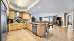 Una cocina moderna con una isla central, electrodomésticos integrados y un comedor con sillas de mimbre.