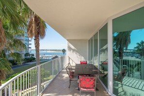 Un balcon avec une table et des chaises, donnant sur une marina et la mer.