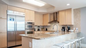 A modern kitchen with stainless steel appliances, a granite countertop, and bar stools. - Large Four Bedroom Unit with Wraparound Balcony Views of the Courtyard! Complimentary Boat Slip! (Orange Beach)