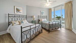 A bedroom with two beds, a ceiling fan, and a large window with curtains. - Large Four Bedroom Unit with Wraparound Balcony Views of the Courtyard! Complimentary Boat Slip! (Orange Beach)
