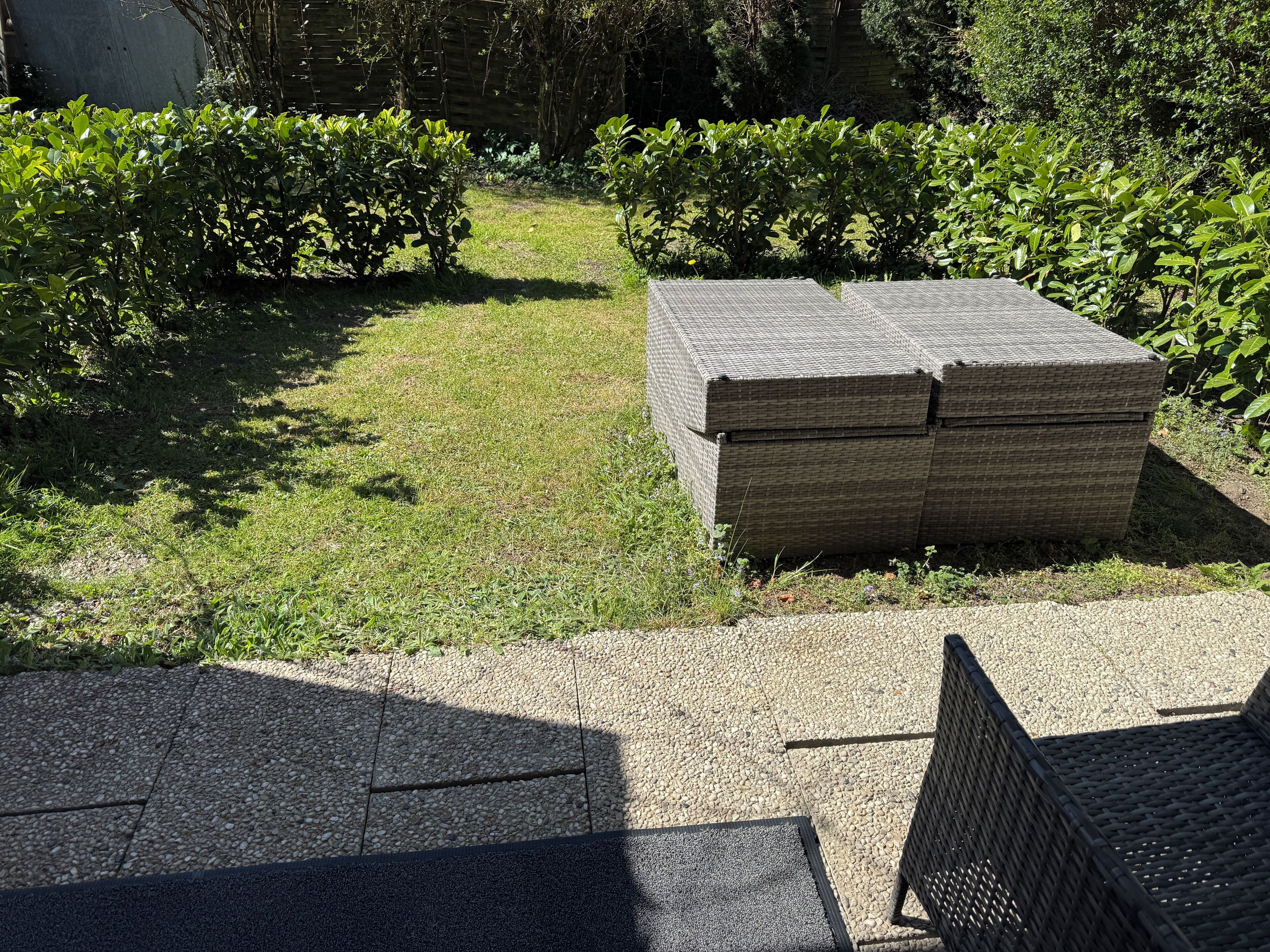 Un jardín con un sendero empedrado, un banco de mimbre y un montón de muebles de mimbre.