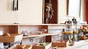 A breakfast buffet with various food items, a statue, and a juice dispenser. - Adler Stube (Münstertal)