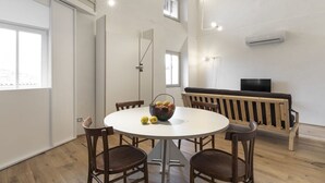 Et moderne interiør med et rundt spisebord, træstole, en bænk, et fjernsyn og et vindue.