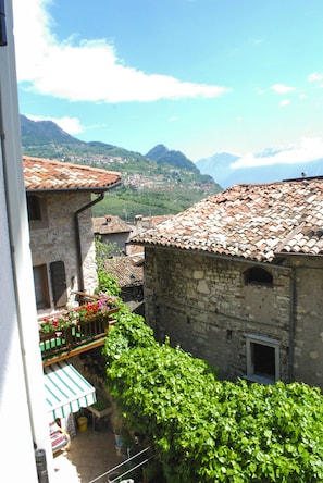 A courtyard with stone buildings, a balcony with flowers, and a mountain backdrop. - La Corte, Gallia by Theater Home, well furnished with lake view (Tignale)