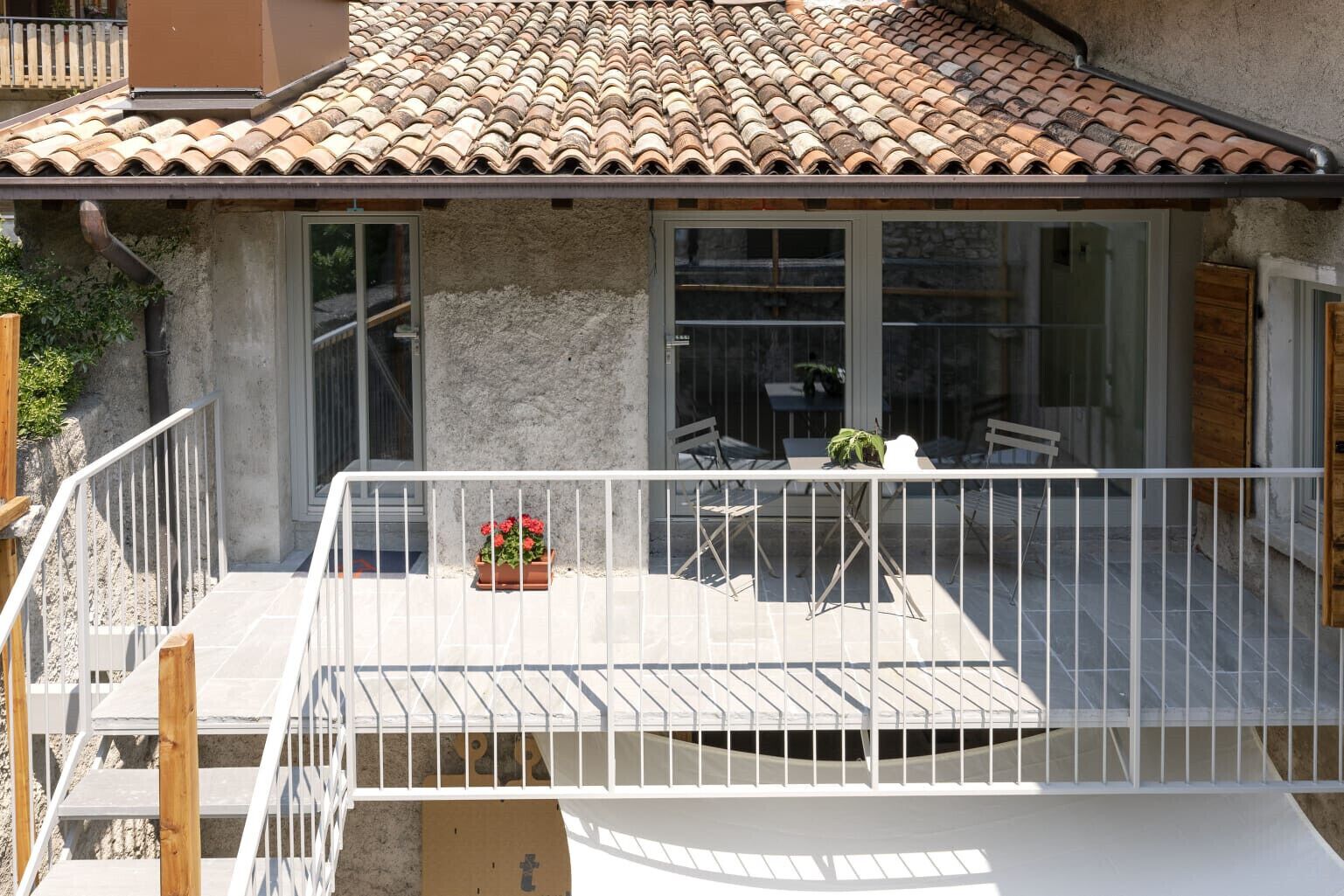 A balcony with a white railing, a table with chairs, and a potted plant.