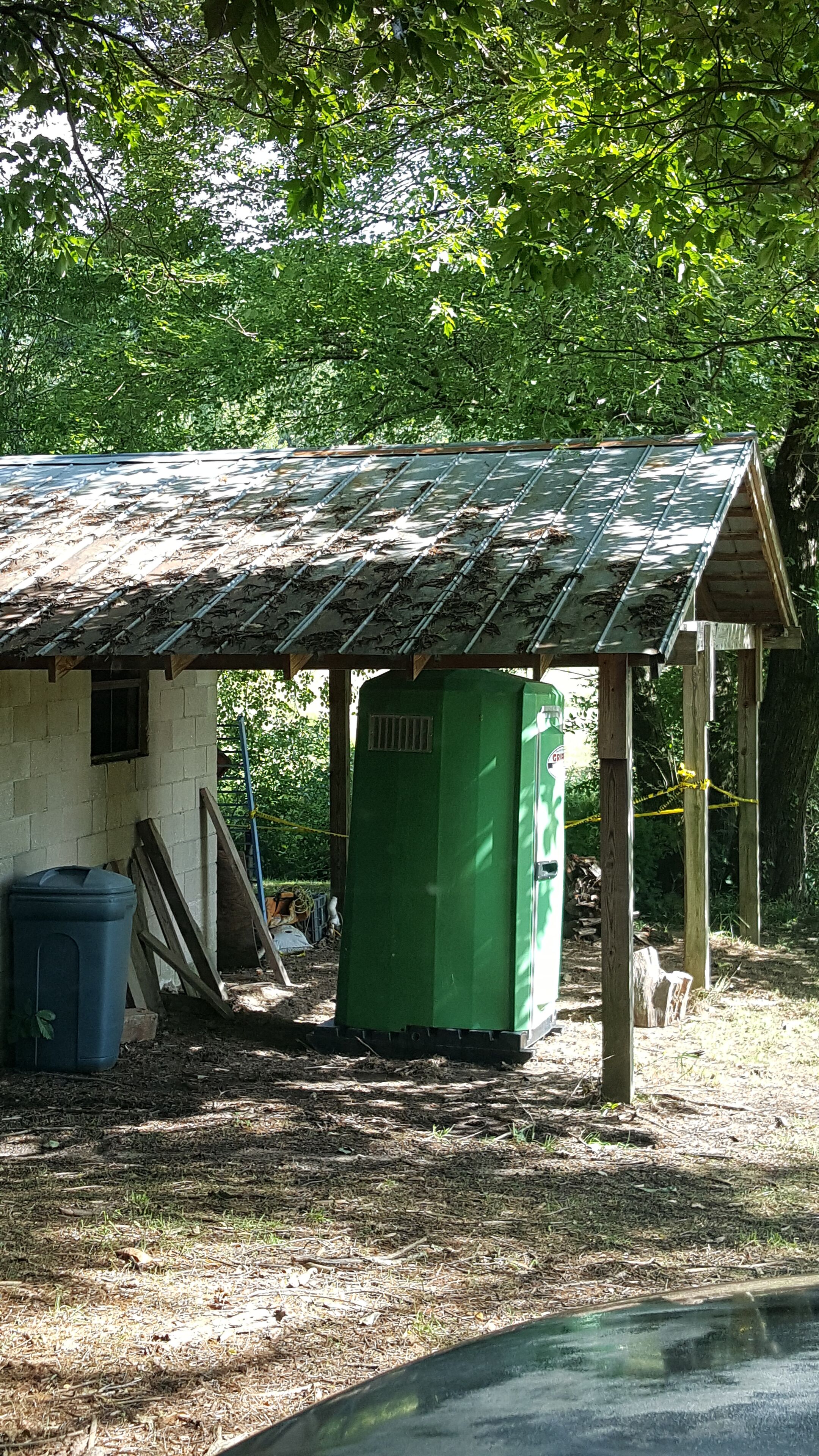 A small, rustic cabin with a metal roof and a green utility box nearby.