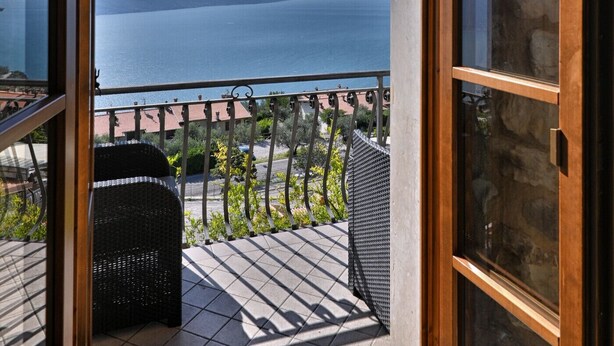 Un balcon ouvert donnant sur la mer et les montagnes.