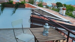 Een terras met een tafel en stoelen, een schotelantenne en uitzicht op bergen.