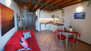 A compact living space with a kitchenette, a dining area, and a sofa with red cushions. - Lince by Theater Home, with pool and lake view (Tignale)