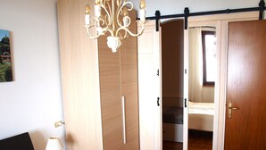Een slaapkamer met een bed, nachtkastje, kledingkast en een kroonluchter.
