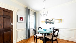 A dining area with a round table, four chairs, a chandelier, and a door with a picture frame. - Spacious Cottage w/ King Bed, Patio, Easy Parking by Lucky Savannah (Savannah)