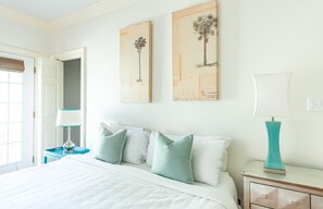 A bedroom with a bed, two nightstands, a door, and two wall-mounted artworks. - Spacious Cottage w/ King Bed, Patio, Easy Parking by Lucky Savannah (Savannah)