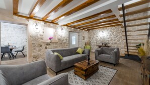 Un salón amplio con pared de piedra, vigas de madera y muebles modernos.